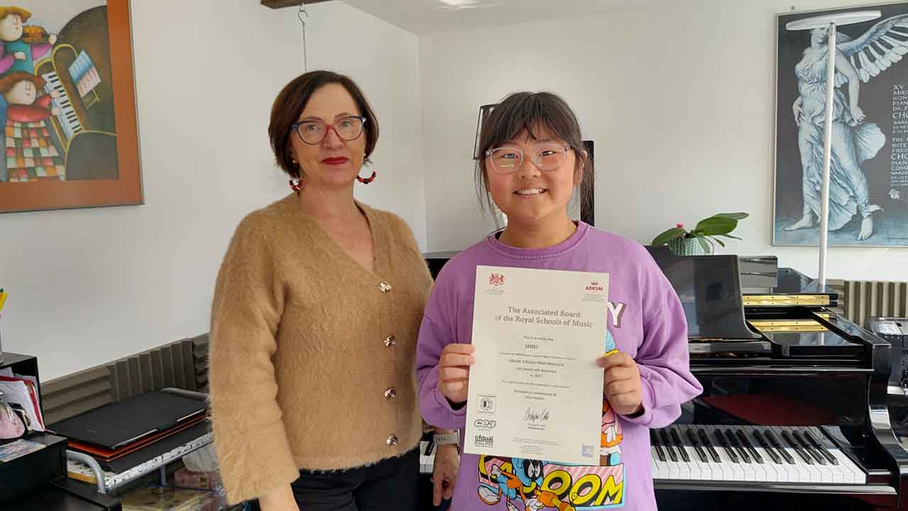 Anna Peszko presenting her pupil Shiyi with her ABRSM Grade 3 Distinction certificate.
